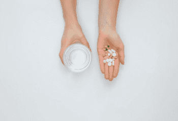 Руки с капсулами Налтрексона для кодирования и стаканом воды